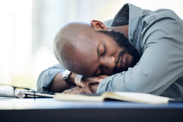 I need a five minute nap. Shot of a handsome young businessman sleeping on his desk in the office.