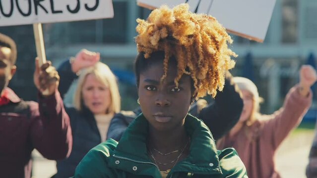 Portrait of female protestor surrounded by marchers holding placards and chanting slogans on demonstration march to promote awareness of black lives matter and racial equality - shot in slow motion