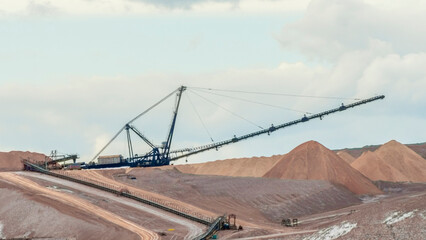 Fototapeta na wymiar Giant spreader or absetzer machinery. A large dumper on a landfill with potash ore. Extracting potassium salts.