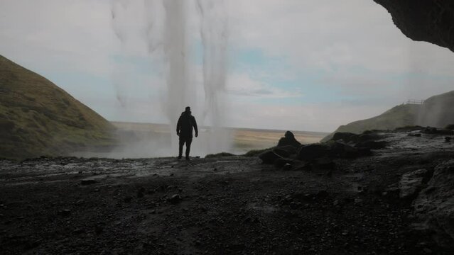 Man Walking Inside The Cave In Seljalandsfoss Waterfall In Southern Iceland. incredible waterfall in Iceland, tourist enjoying amazing view of Iceland nature. Wide angle shot, high quality 4k footage