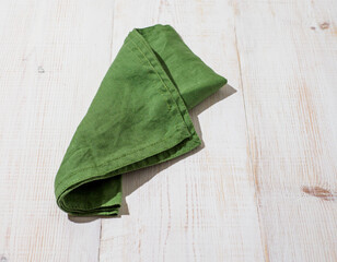 Green linen kitchen towel or textile napkin on white wooden background.