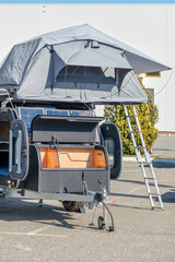 Camper, a small mobile home on wheels as a trailer to a car in a parking lot.