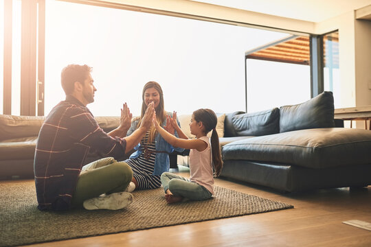 Family time is even better when youre having fun. Shot of a happy family of three playing a clapping game together at home.