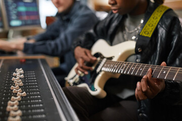 Close up of young black woman playing guitar and singing while composing music in professional...