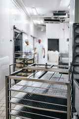 Manual workers in cheese and milk dairy production factory. Traditional European handmade healthy food manufacturing. Focus on foreground.