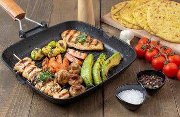 Grilled chicken breast and souvlaki  with different vegetables in a pan.