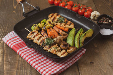 Grilled chicken steak in different variations with avocado, carrot, mushroom and brussels sprout on a teflon pan.