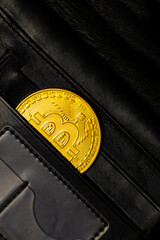 a gold-colored bitcoin coin in a wallet pocket. bitcoin in the wallet.