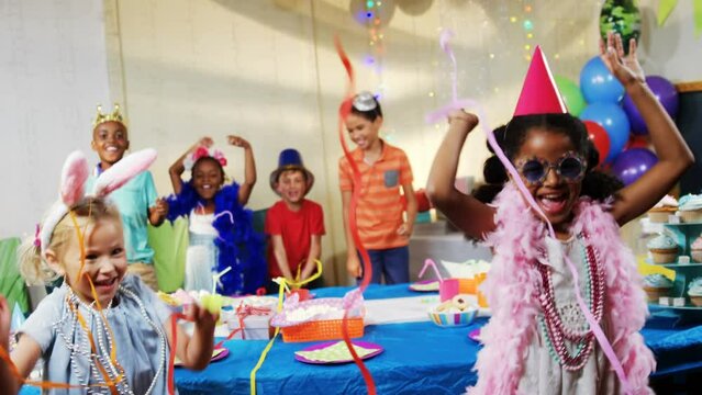 Animation of confetti falling over diverse children dancing at birthday party