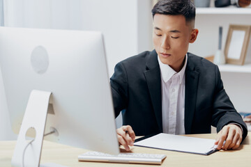 Fototapeta premium manager in a suit glass of coffee sits at a tablein front of a computer Lifestyle