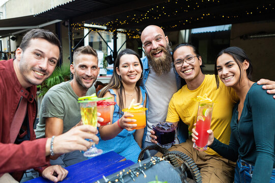 Group Portrait Of Multiracial Young People Cheering And Toasting With Trendy Cocktails - United Diverse Friends Having Fun Drinking Alcohol On Summer Vacation - Focus On Asian Woman Face