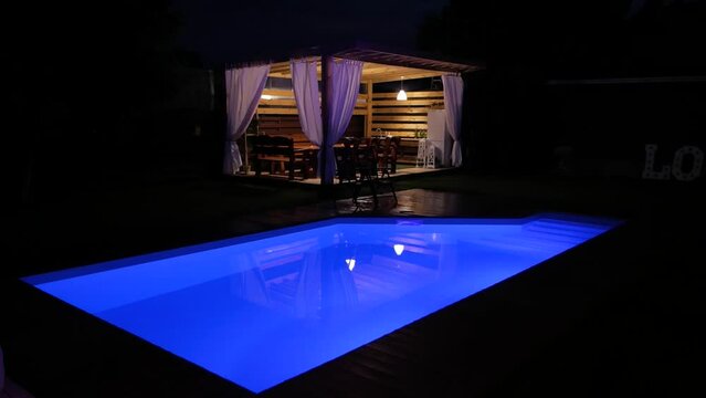 Outdoor night swimming pool with water night lighting, which changes color from blue to green