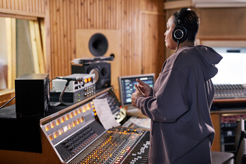 Side view portrait of female music producer showing thumbs up while supporting band in recording...