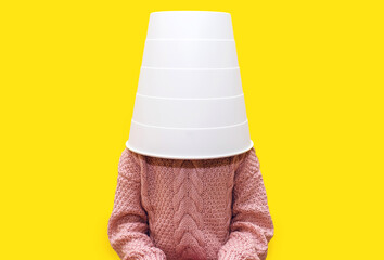 Girl child with a bucket on her head on a yellow background. Funny child put a white bucket on his head. Child playing with a bucket on a yellow background © halcon1