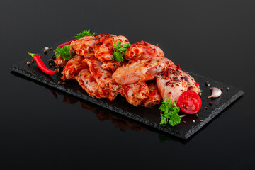 Сhicken wings in marinade on a black plate
