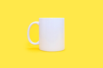 White mug on a yellow background in the center. White cup with any drink on an empty yellow background. Cafe or snack concept. White mug with the possibility of applying advertising or logo