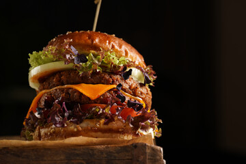 Hamburger with double angus beef patty, tomatoes, lettuce, cheese and barbeque sauce on wooden...