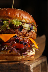 Hamburger with double angus beef patty, tomatoes, lettuce, cheese and barbeque sauce on wooden...