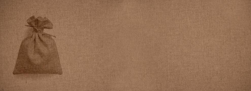Tied fabric sack made of canvas over a canvas-like background of a coarse woven hard fabric