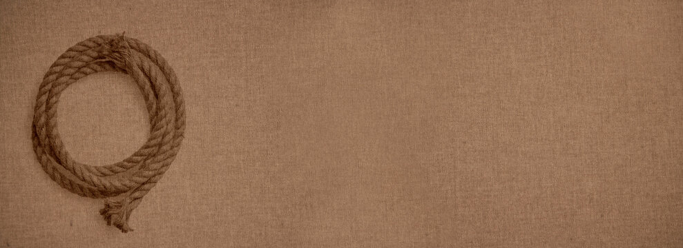 Thick sailing rope coil over a canvas-like background of a coarse woven hard fabric