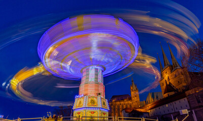 Old brightly lit chain carousel at night at a German fair, Oktoberfest and Christmas market in...