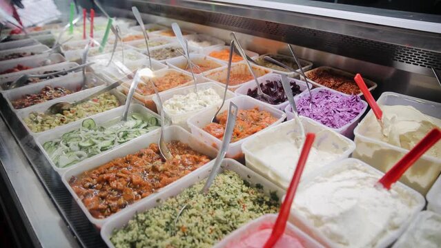 Tracking view of different kind of fresh salads, sauces and hummus that is on the sale in the market of Tel Aviv, Israel. Prepared take away food