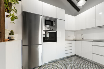 Kitchen with white wooden furniture combined with white stone countertop, column with cabinets, ceramic hob and oven and microwave oven and hydraulic stoneware floors