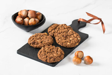 Vegan Chocolate oatmeal cookies with hazelnuts on a serving board. White background