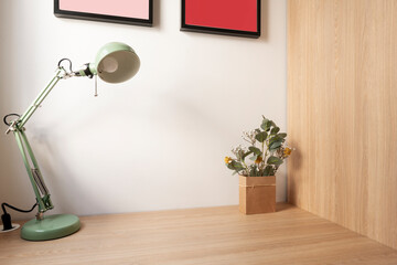 Corner of a room with a wooden wardrobe and matching desk with a pale green metal lamp and a...