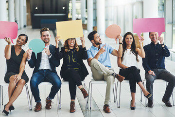 Say it as it is. Shot of a group of cheerful businesspeople holding up speech bubbles inside of the office during the day.