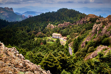 casa grande o mansion entre las montañas y un gran bosque verde con un cielo nublado en mineral...
