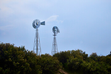 molinos de viento con un cielo medio nublado y arbustos en la parte baja en monte escobedo...