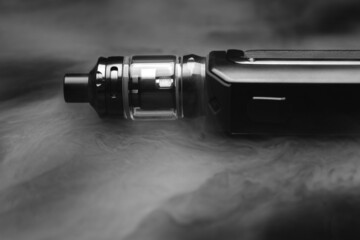 Electronic cigarette in smoke on a black background, smoking nicotine through an electronic...