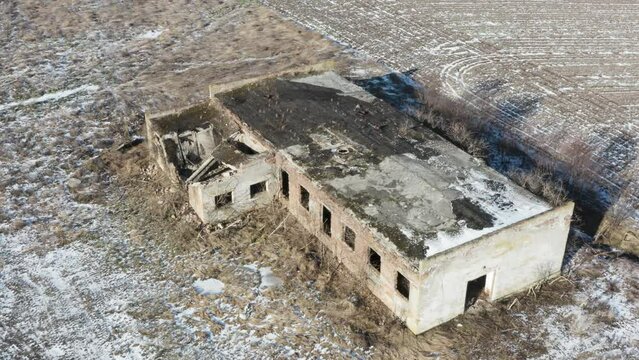 Aerial view of an abandoned industrial building near the agricultural field. Winter time