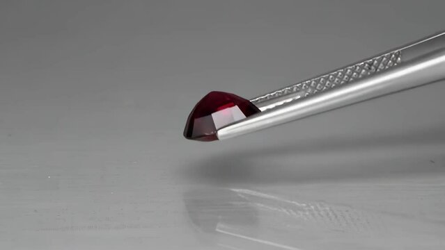 natural red rhodolite gemstone oval cut in the tweezers