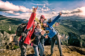 Happy friends hikers with backpacks taking selfie portrait on the top of mountain - Smiling happy climbing tourists enjoying summer holidays at high altitude - Freedom, success sport concept - obrazy, fototapety, plakaty