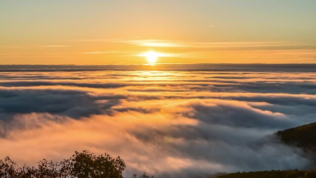 Timelapse time lapse of inversion clouds at sunrise morning in Wintergreen Resort, Virginia ski town with colorful red sun rising above horizon with sunlight sky in Blue ridge mountains