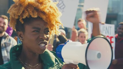 Group of protestors with megaphone holding placards and chanting slogans on demonstration march to promote black lives matter anti racist beliefs - shot in slow motion