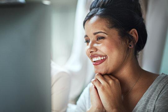 Good reviews make her day. Shot of a happy young businesswoman looking at her computer screen while sitting in the office.
