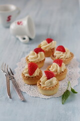 Shortbread cookies with cream and strawberries, food composition with forks and cups on a light blue background, patisserie