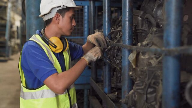Old car alternators on shelf. Engineer man and Foreman wearing safety helmet standing at recycling yard of old industrial vehicle. 