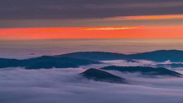 Timelapse time lapse of inversion clouds at sunrise morning dawn in Wintergreen Resort, Virginia ski town with colorful red sun rising above horizon with sunlight sky in Blue ridge mountains