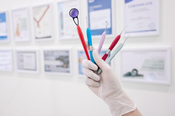 Gloved hand holding dental instruments in dental office