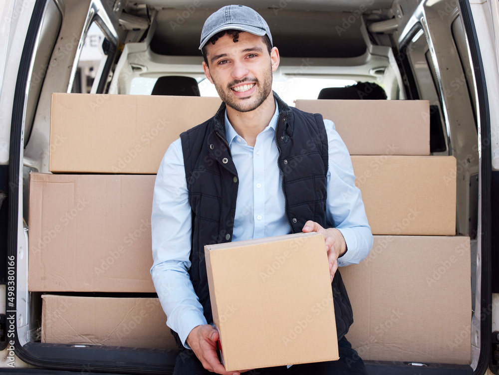 Poster on my way to drop-off the next box. portrait of a young delivery man loading boxes from a van.