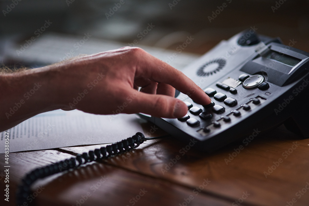 Poster success is a phonecall away. shot of an unidentifiable businessman using a desk phone in the office.