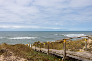 Obraz premium Wooden Boardwalk Leading Through Coastal Dunes to the Ocean