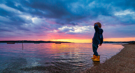 Fototapeta na wymiar Little boy in yellow rubber boots by the sea, Portugal Seascape - Lagoa de Óbidos