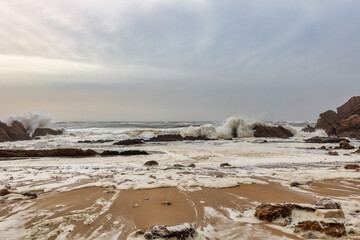 Wild Sea in Portugal near Nazare with Foamy Waves Crashing against Rocky Cliffs