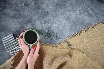 A cup of green seaweed powder in the hands of a young girl