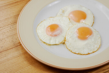 fried scrambled eggs from three eggs on a wooden table